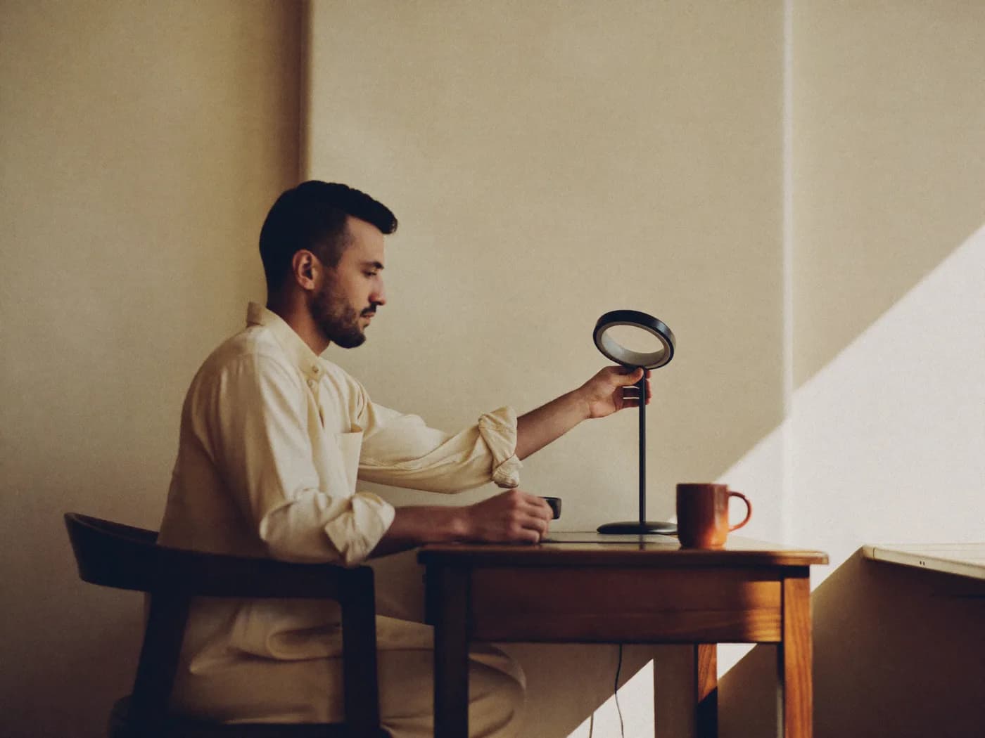 A creator at a sunlit desk, adjusting a small ring light before going live.